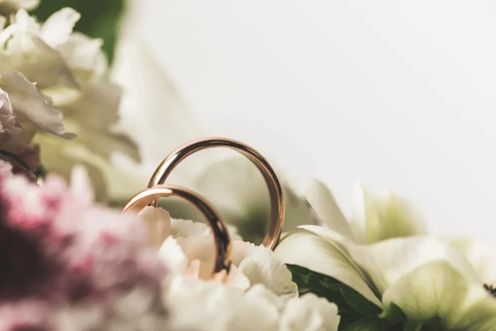 Flowers and two gold wedding bands.