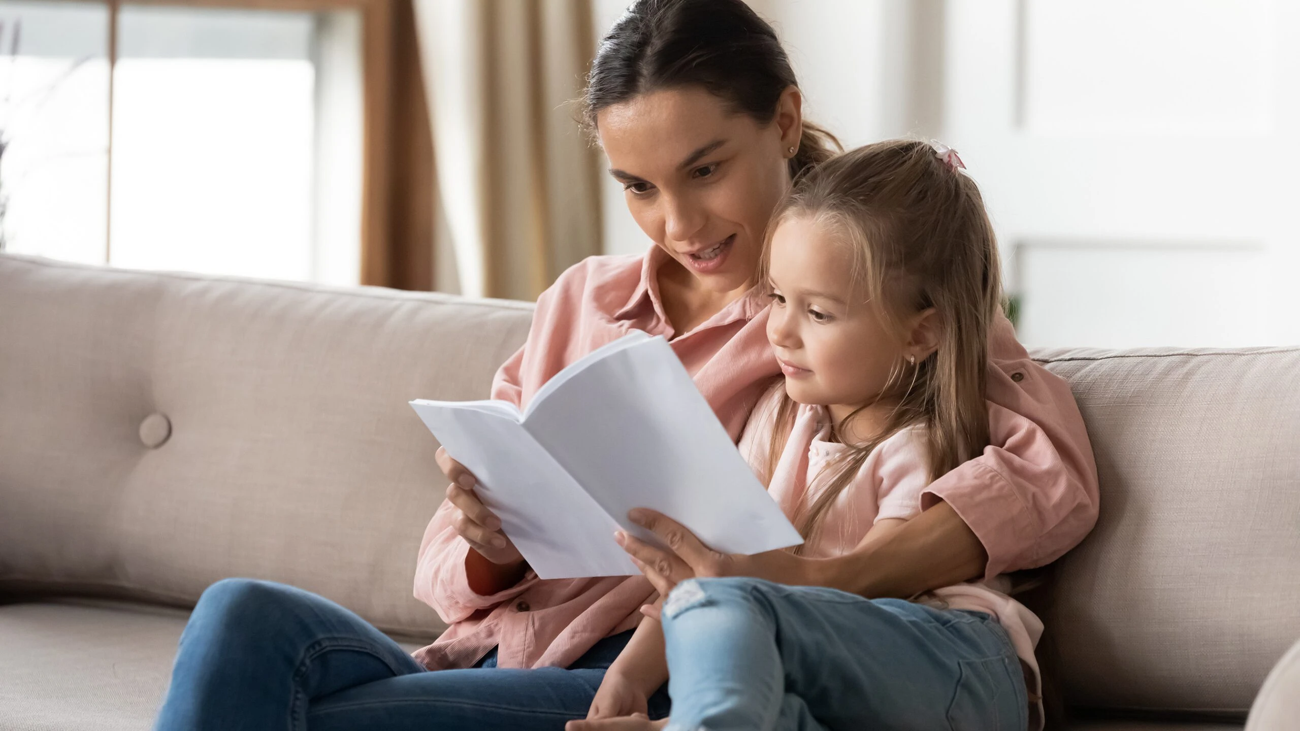 A mom and daughter sitting together reading a book. If you are the custodial parent in a divorce, a Houston Child Support attorney can help you figure out how much child support you’re entitled to.