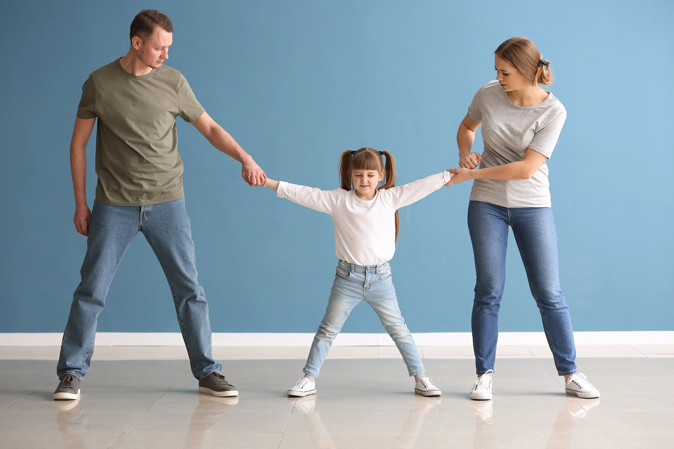A little girl standing between her mom and dad while they pull her in each direction. Divorce is never easy for kids or adults, but a child custody lawyer in Houston or Sugar Land can help your family reach a favorable custody agreement.