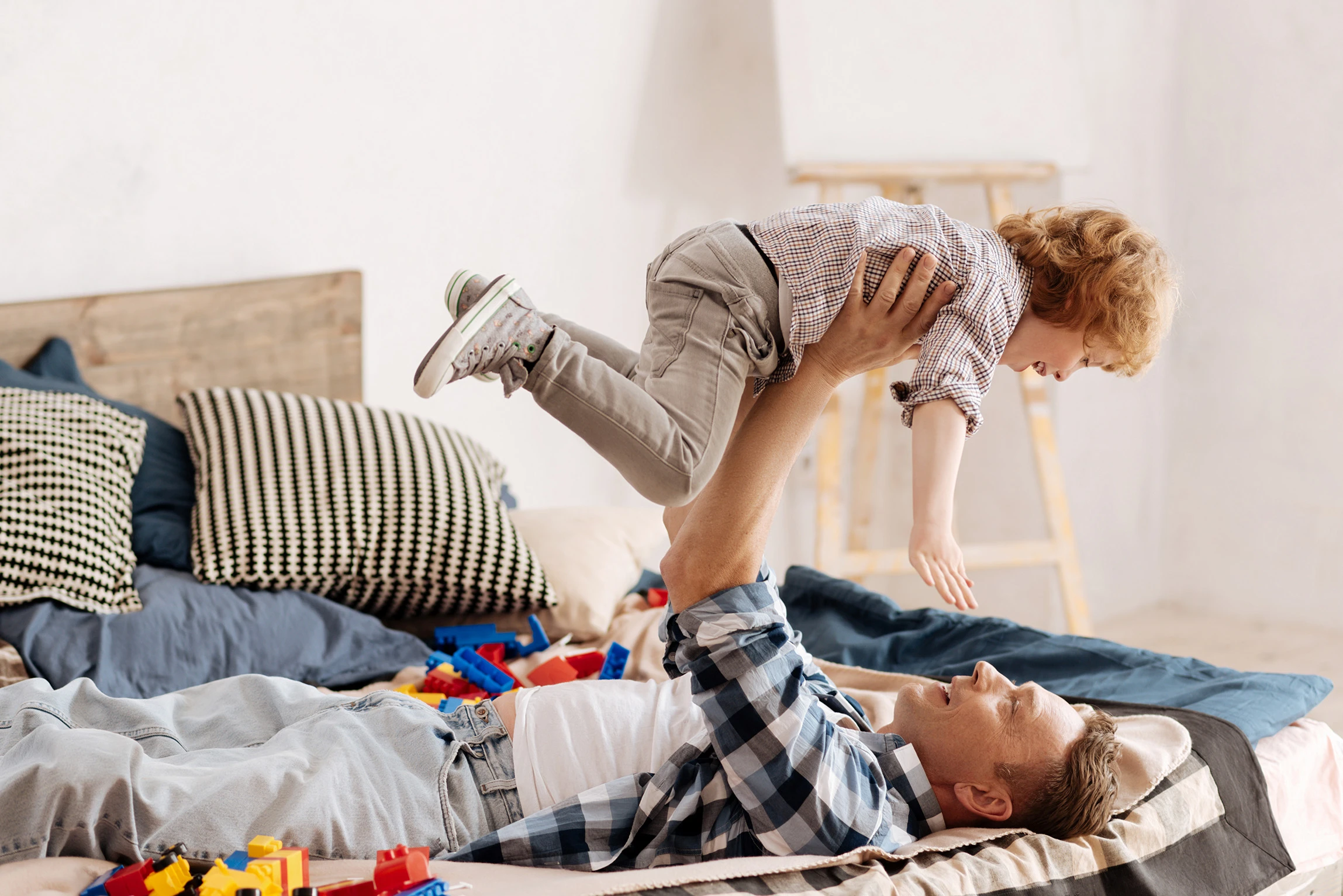 Dad laying down and holding son over him playfully. It takes a lot to raise a child and a Houston family law attorney can help you get the support you need to raise your child with less financial strain.