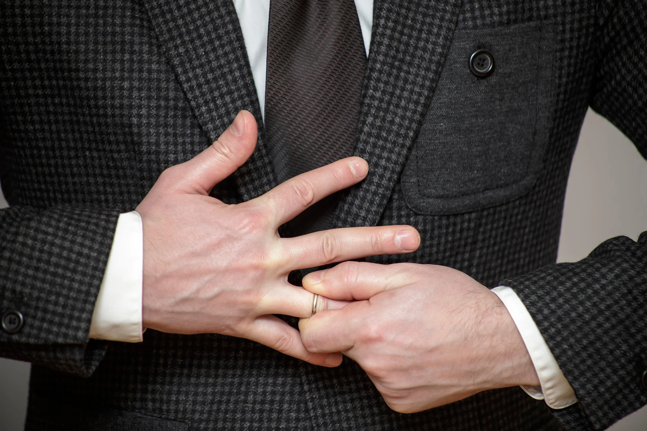 Man in suit removing his wedding ring. If you’re a man going through a divorce, our Houston divorce attorneys for men are here to guide and support you.