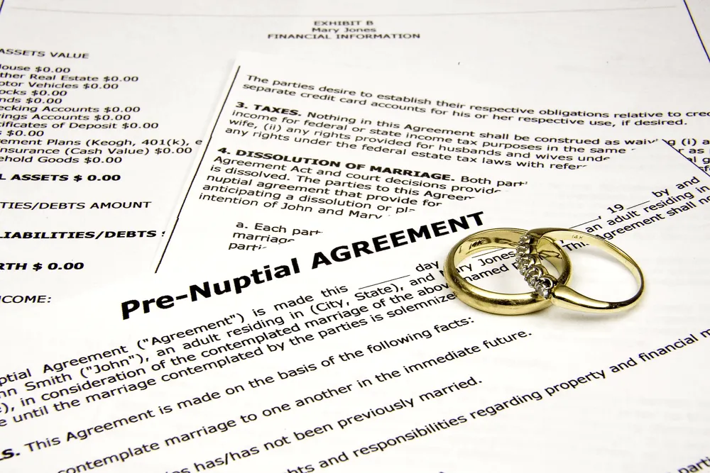Pre-nuptial agreement papers with two wedding rings on top. 