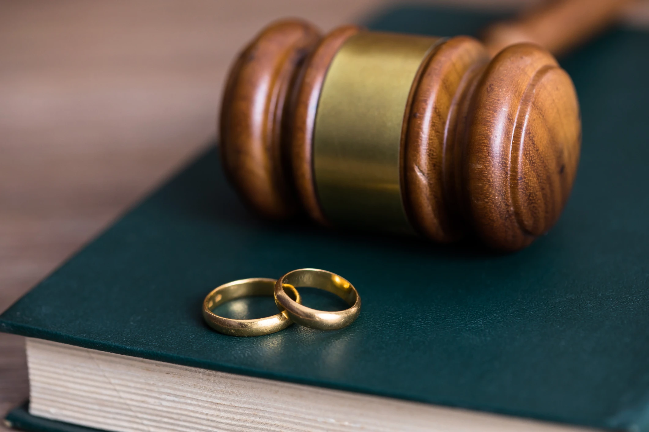 Two golden wedding rings on a book with a judge gavel representing divorce. Our Houston divorce lawyers can help you if you're ready to file for divorce.