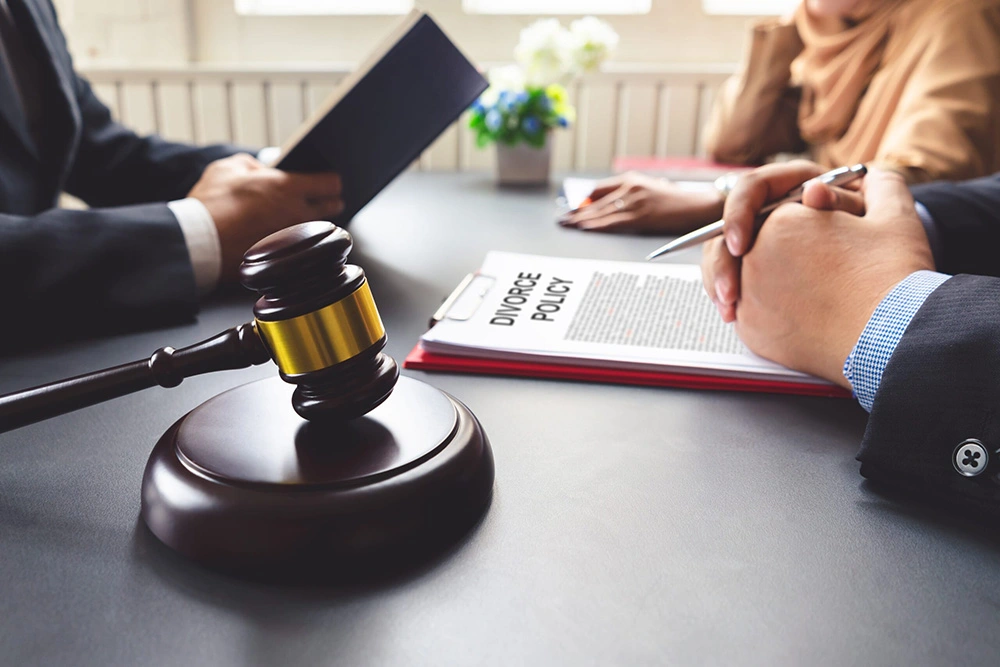 Man holding book sits across table from woman and man with divorce policy papers in front of them. In working with our Houston divorce modifications lawyer, our experts will help guide you through the stressful legal divorce proceedings.