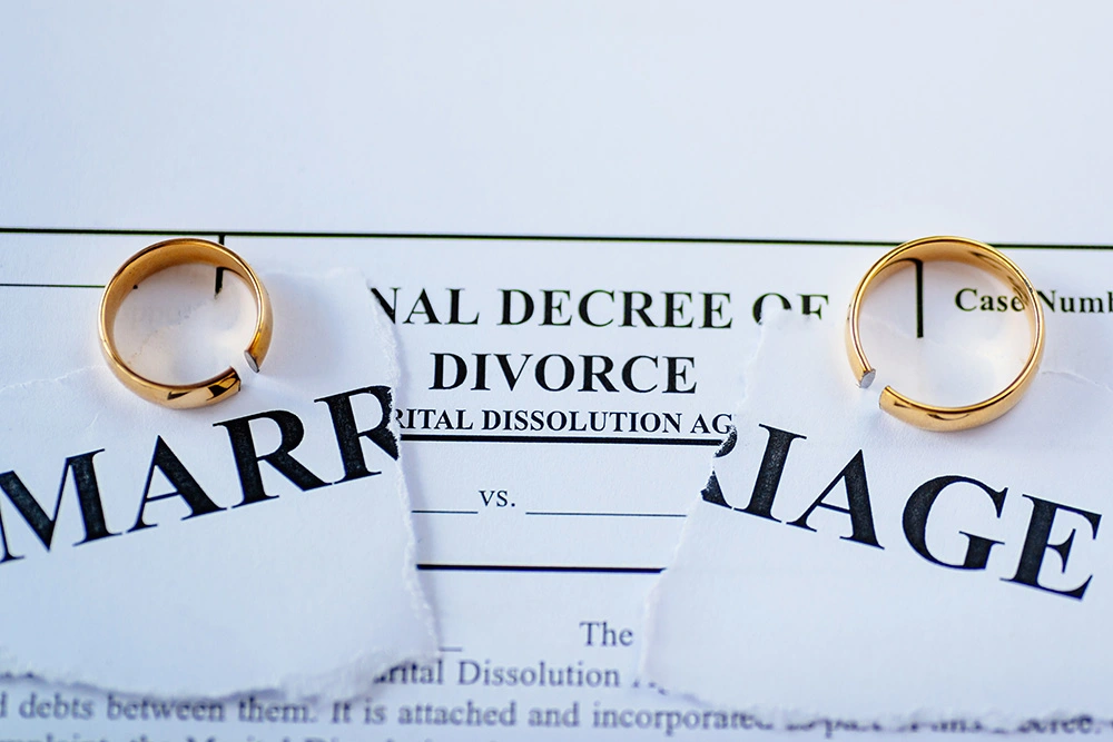 Two wedding rings sitting on a torn up divorce decree. If you're ready to leave your marriage, our Katy divorce lawyers are ready to fight for you.