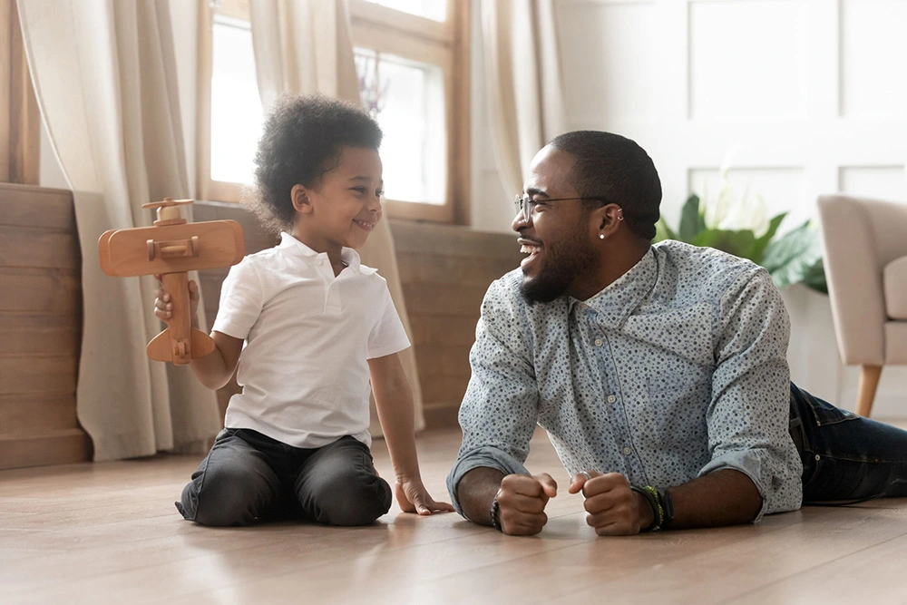 Father and son joyfully playing on the floor together as son holds a toy airplane. Our Sugar Land father’s rights lawyer will protect your rights to see and be part of your child’s life.