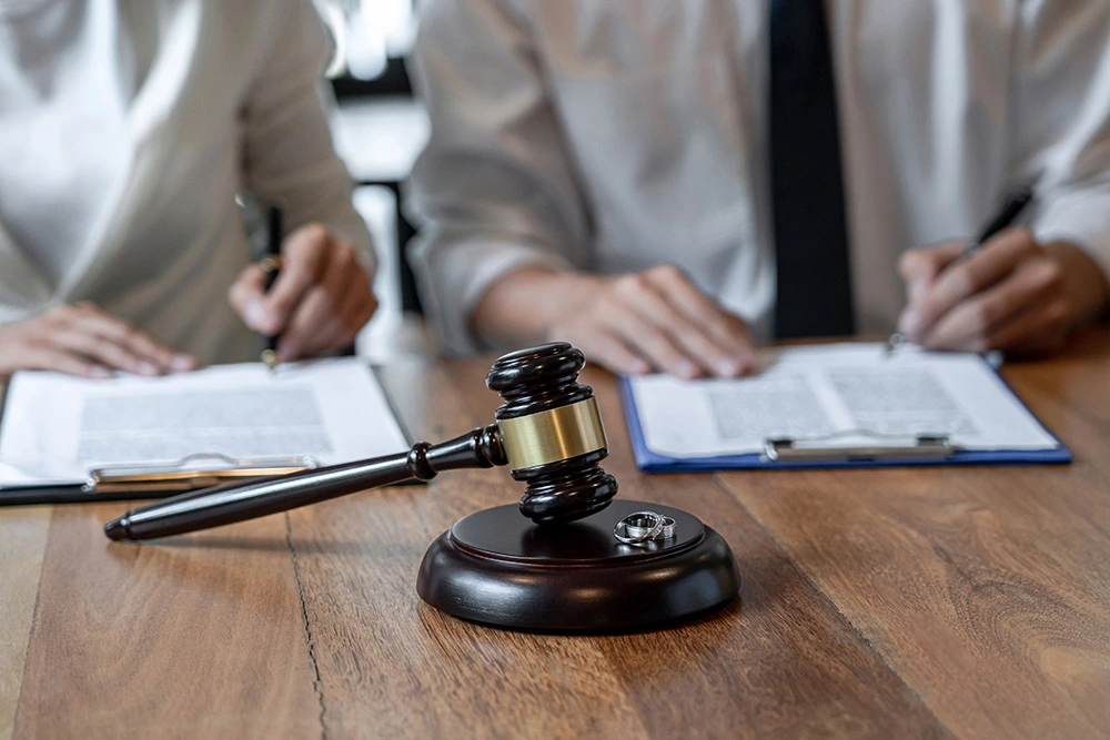 A couple signing divorce documents behind a judge gavel and two wedding rings. If circumstances have changed and you need to modify a divorce decree, contact a Cypress divorce modifications lawyer now.