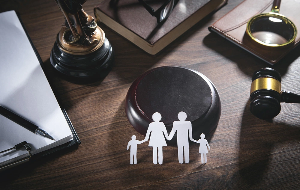Paper cut family, judge gavel, book and other objects on desk representing family law. If you're going facing any family law issue, the Houston family law lawyers at Skillern Firm are ready to fight for you.