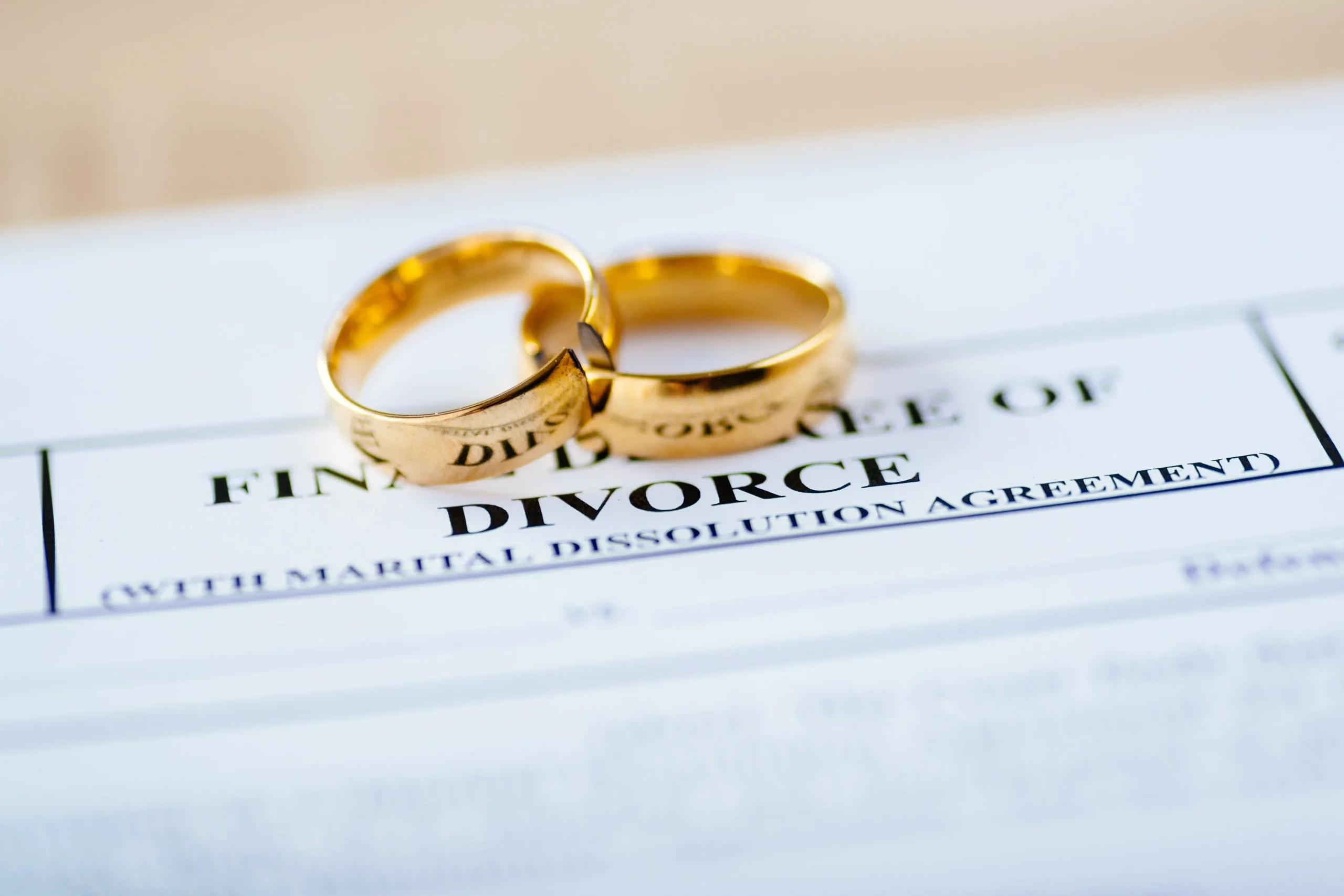 Final decree of divorce paper with two wedding rings on top. 