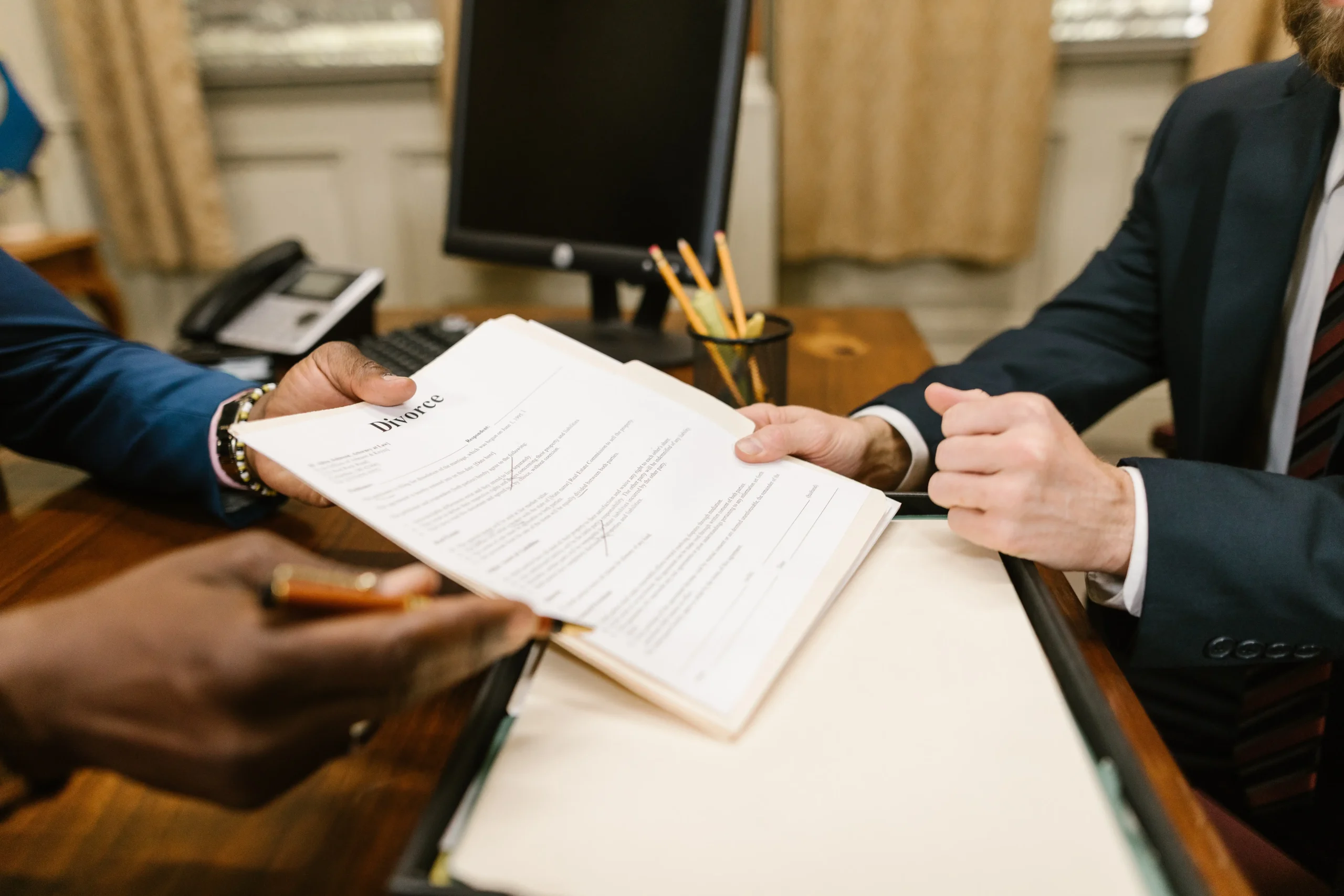 Close up of a lawyer's hands showing a client where to sign.